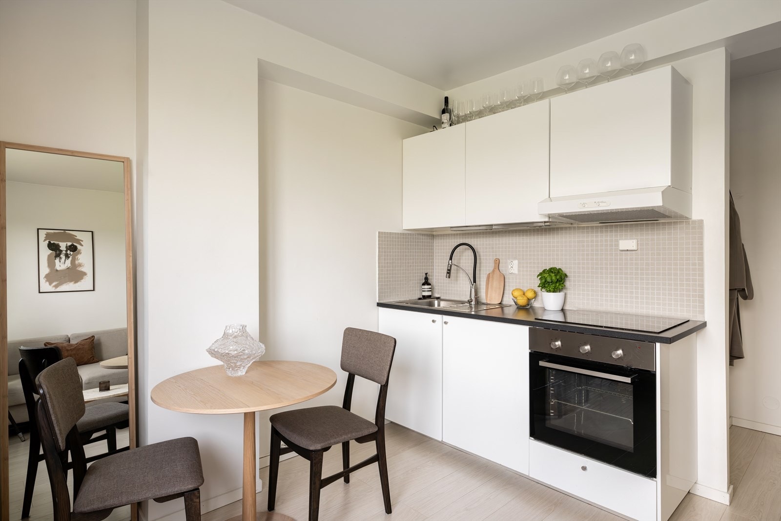 Pent og tidløst kjøkken som er utstyrt med integrert kjøleskap, platetopp, stekeovn og frittstående oppvaskmaskin. Galleribilde