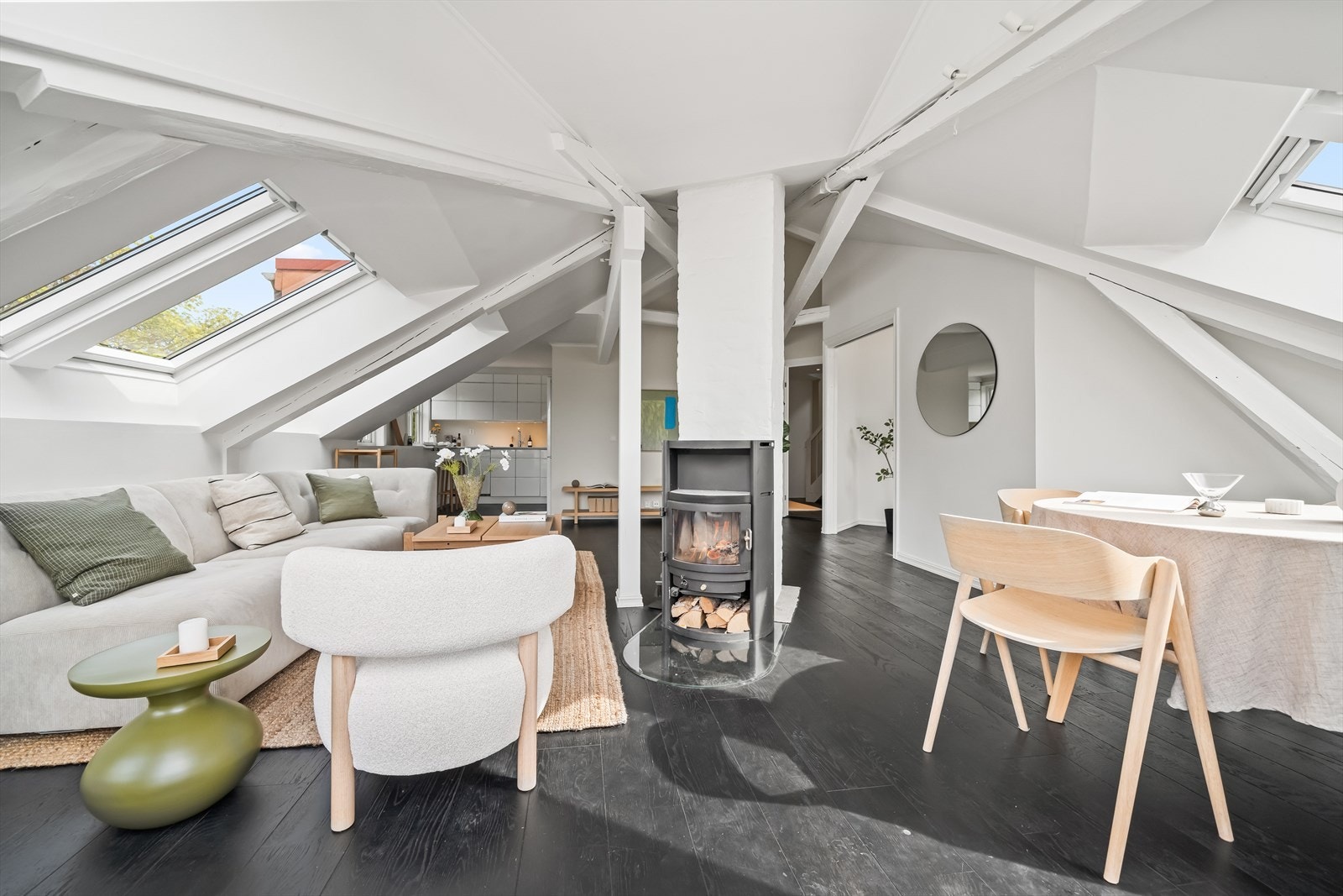 Stor og lys hjørnestue med peis og delvis åpen kjøkkenløsning. Galleribilde