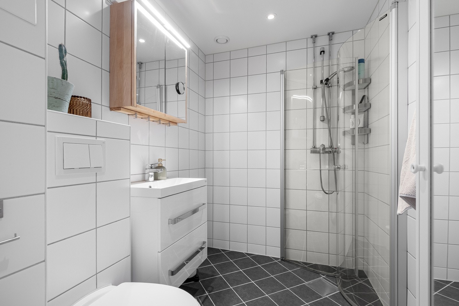 Innbydende og tidløst flislagt baderom som ble pusset opp sammen med rørutskiftning i regi av borettslaget i 2016. Galleribilde