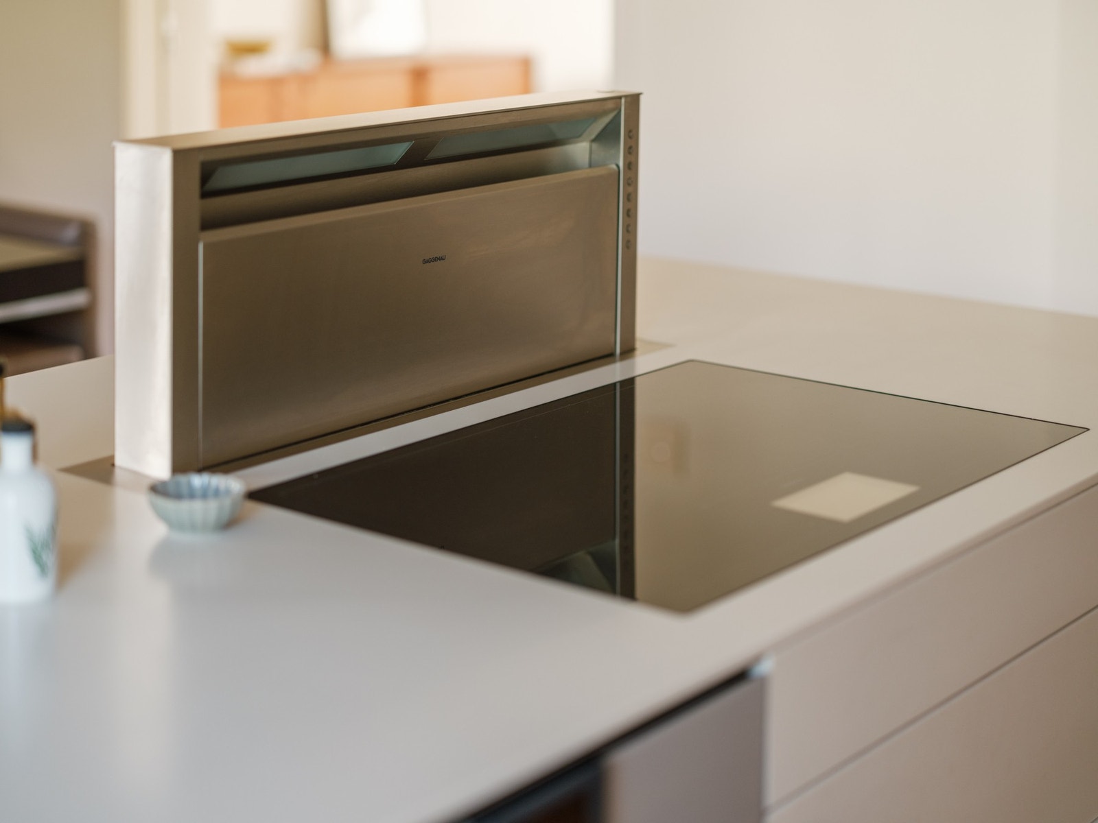 Ventilator med avtrekk ut, ned gjennom gulvet under kjøkkenøy, ned i vaskerom og ut, alt fra Gaggenau. Galleribilde