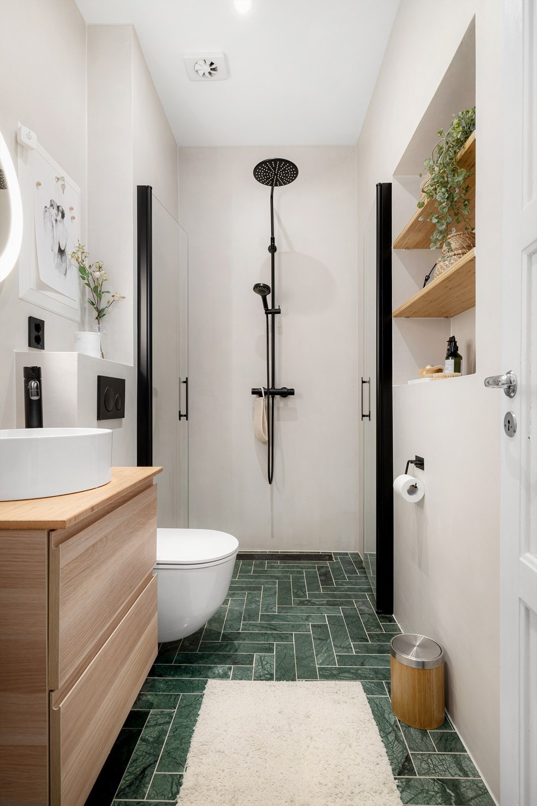 Gulvfliser i indisk grønn marmor fra Ulfven og vegger kledd med mikrosement. Gulvvarme, smarte integrerte vegghyller og doble svingbare dusjdører. Galleribilde