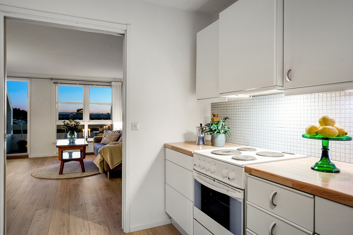 Kjøkkenet har en innredning med slette fronter og mosaikkfliser over benkeplaten av laminat Galleribilde