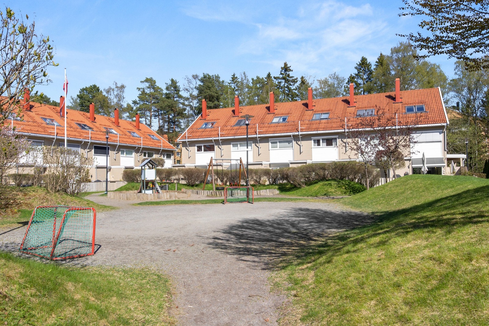 Hyggelig tun mellom byggene med lekeplass, fotballøkke og sittebenker til felles anvendelse Galleribilde