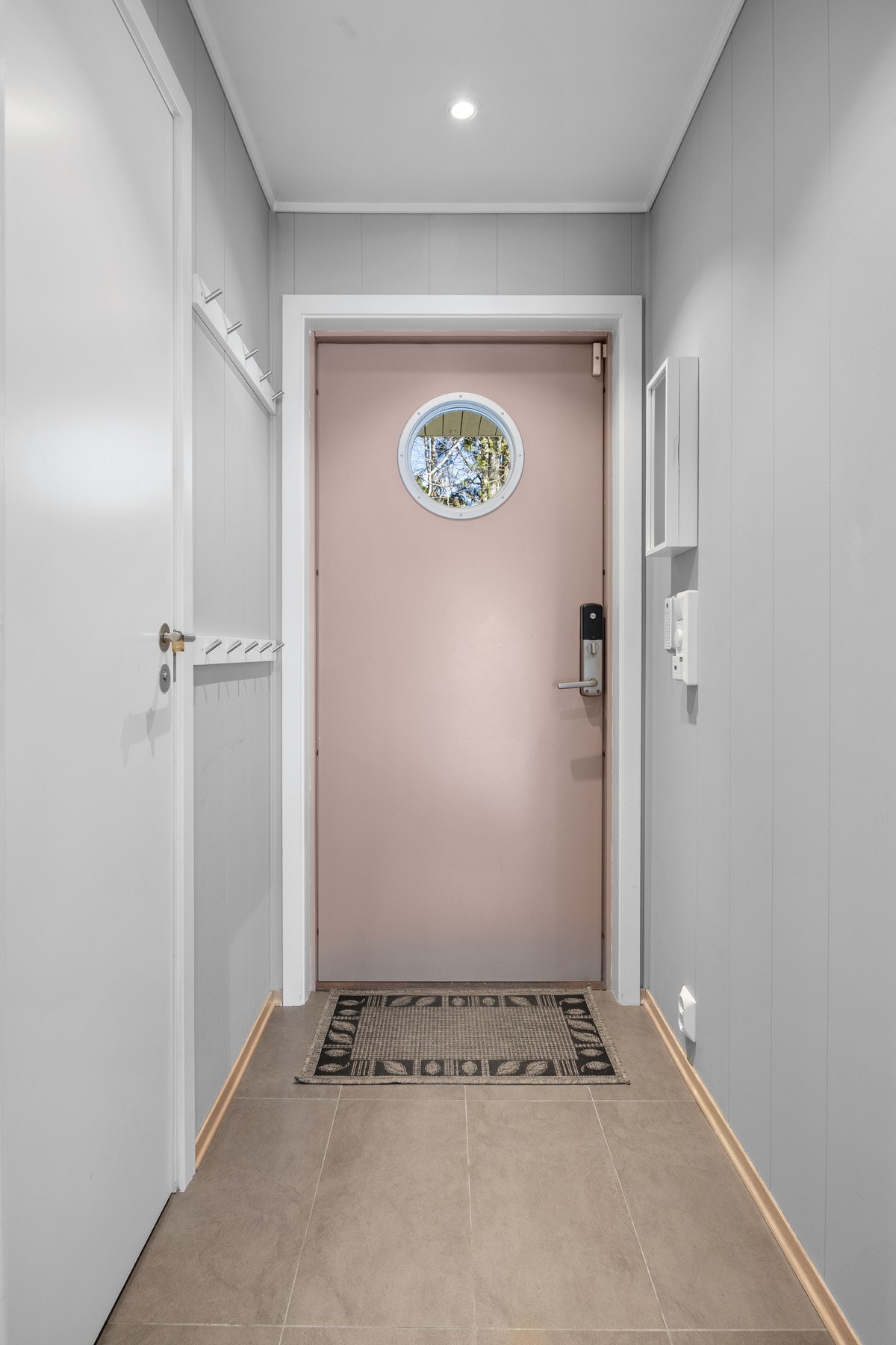 Vel innenfor blir vi ønsket velkommen i en fin entré med lysegrå vegger, downlights i himlingen og lyse fliser på gulvet Galleribilde