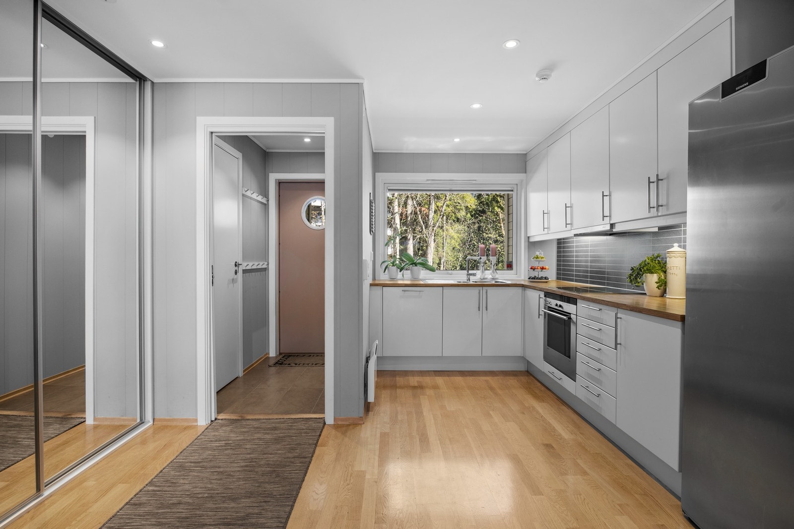 Innredningen har hvite, glatte fronter, takhøye skap og gyllen laminatbenkeplate med nedfelt kum i stål Galleribilde