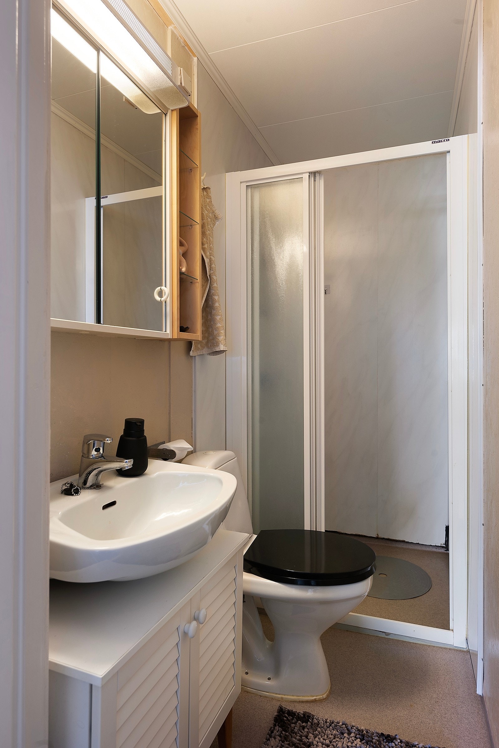 Leiligheten har et bad. Badet har belegg på gulvet og plater på veggene og er innredet med servant, toalett og dusjnisje. Badet må oppgraderes for å tåle normal bruk etter dagens krav Galleribilde