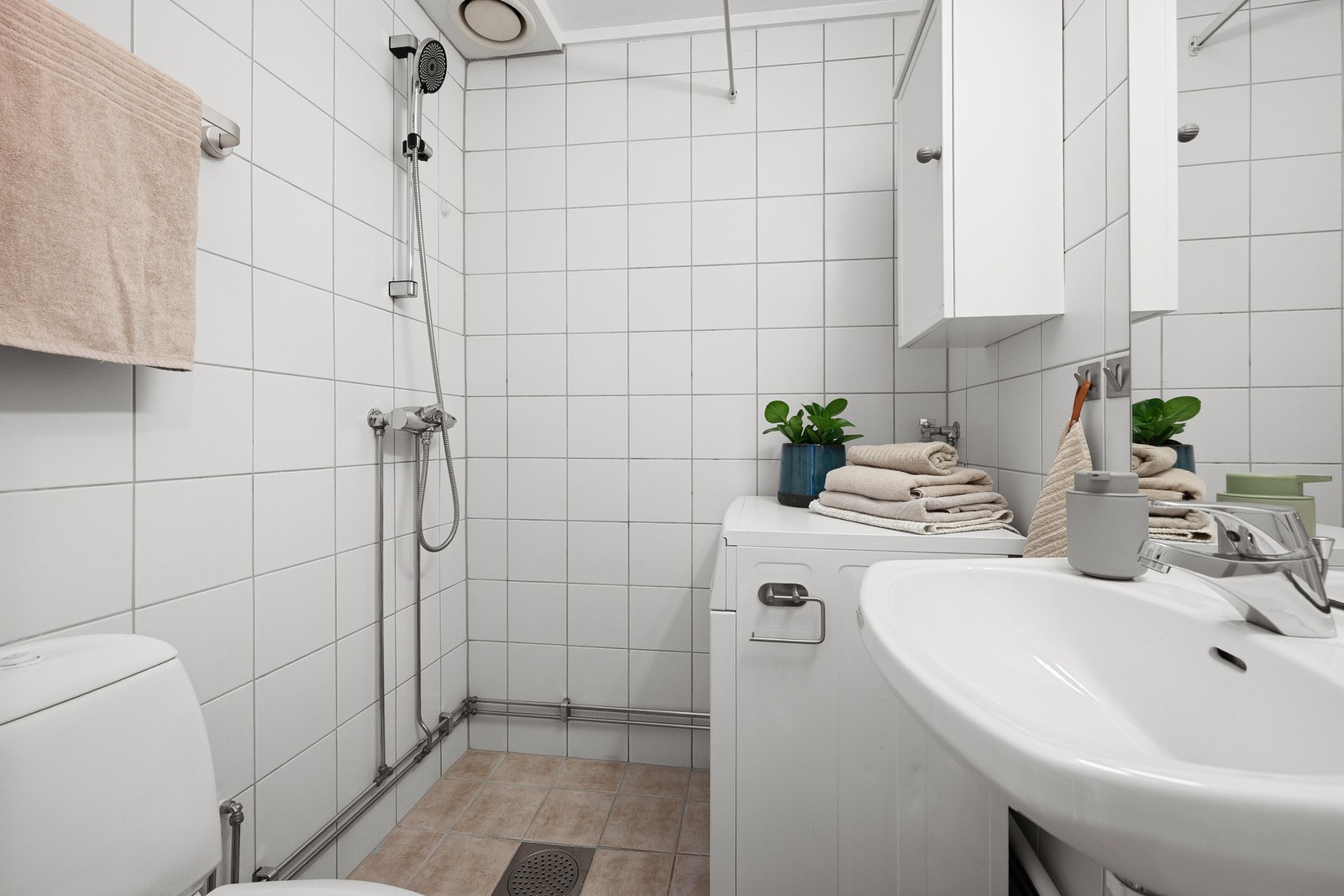 Flott, flislagt bad med gulvvarme med opplegg for vaskemaskin. Galleribilde