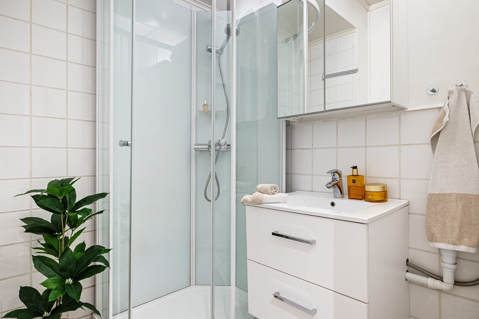 Badet er på 2,6 m² og har fliser på gulv og vegger. Det er utstyrt med nyere dusjkabinett og servantløsning. Galleribilde