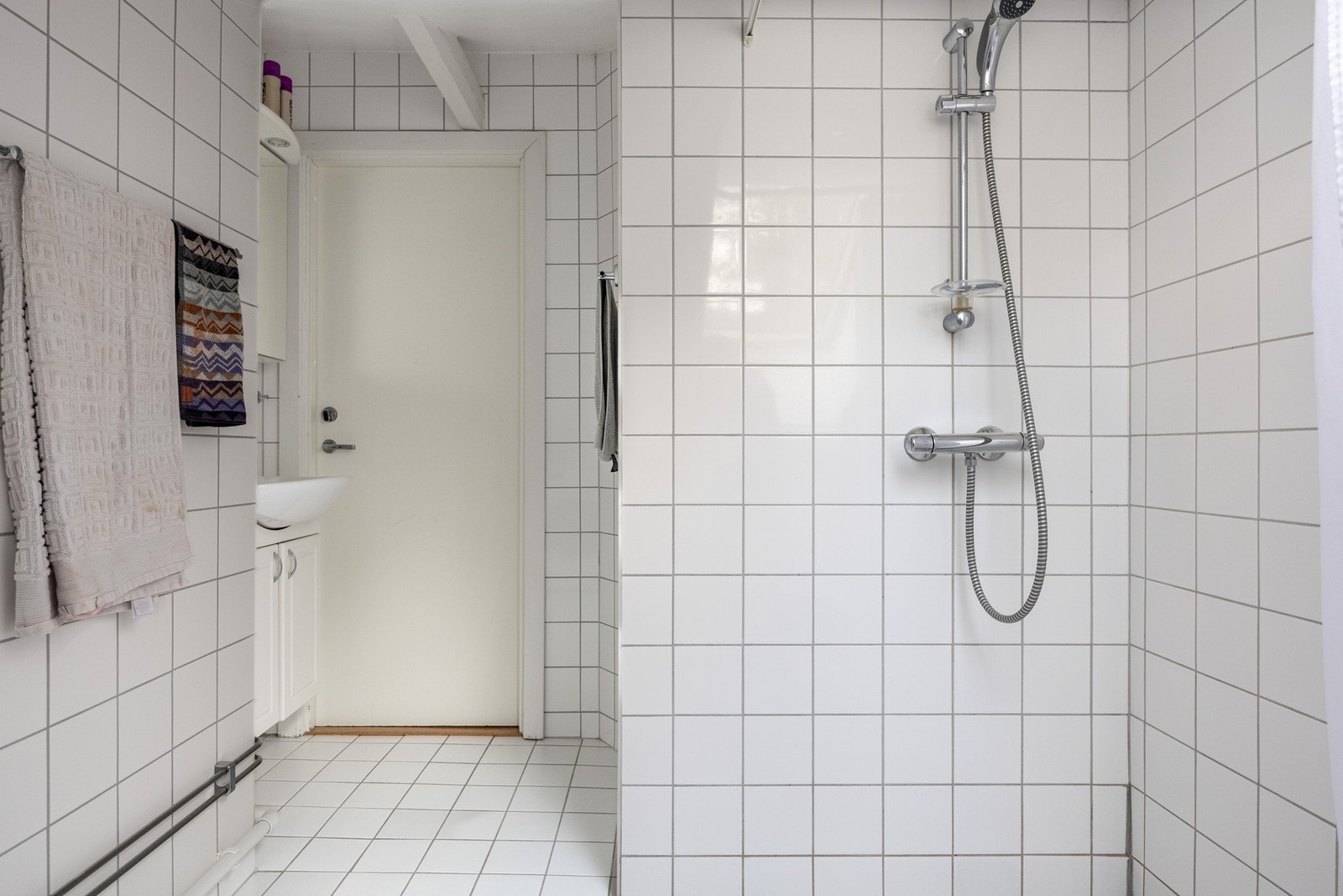 Rommet er innredet med veggmontert toalett, servant med servantskap, speilskap med belysning og et nedsenket dusjhjørne med forheng. Badet har opplegg for vaskemaskin. Vaskemaskinen medfølger salget. Galleribilde