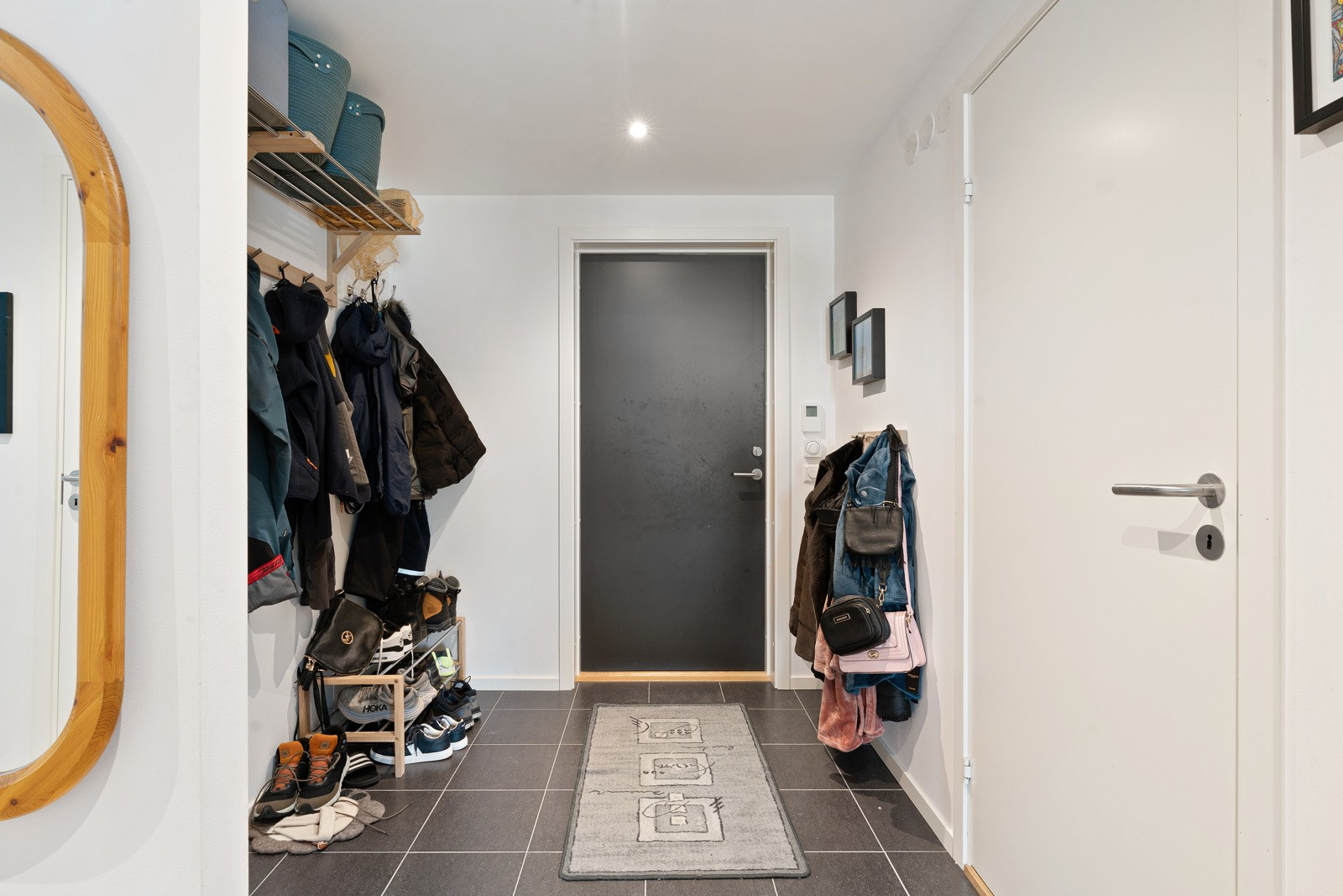 Romslig entre med fliser på gulv, gulvvarme og downlights i himling. God plass til skoskap, kommode og garderobeløsning.