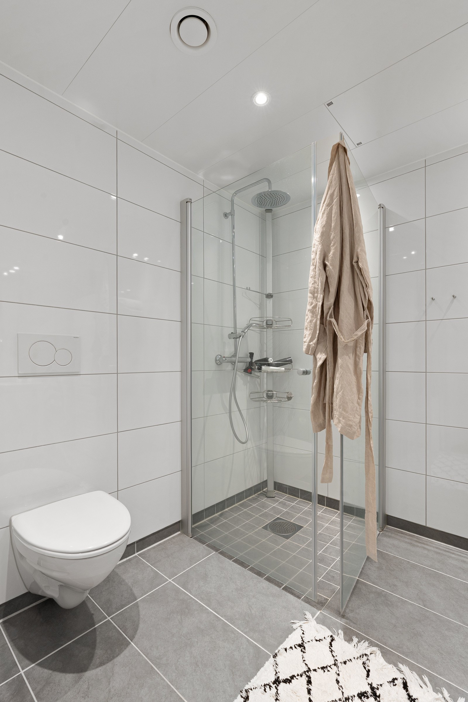 Badet har vegghengt wc, dusjhjørne med regndusj, hånddusj og innfellbare glassdører. Forbruk av varmtvann er inkl.