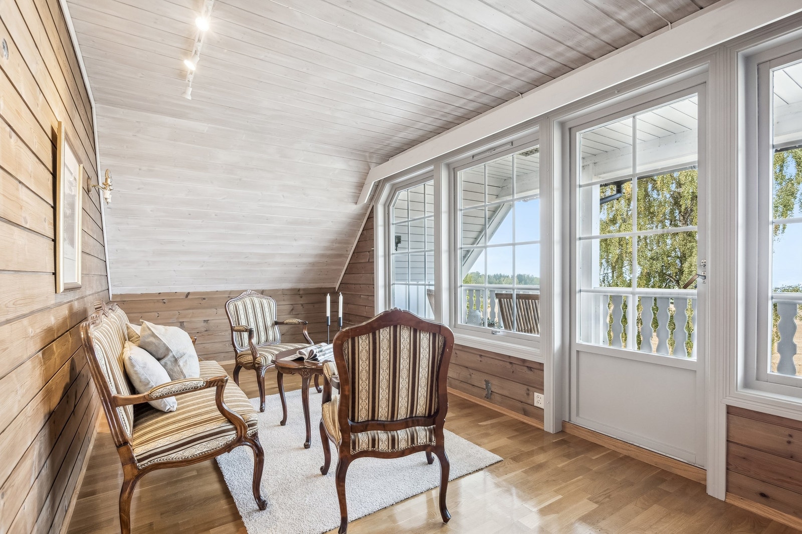 Loftstuen har parkett på gulv og vegger med panel. Utgang til en koselig overbygd balkong. Galleribilde