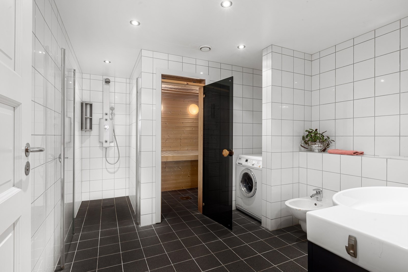 Badet er av meget god størrelse, og inneholder dusjnisje med blandebatteri med flere funksjoner, badstue, opplegg for vaskemaskin, bidé og servantinnredning Galleribilde