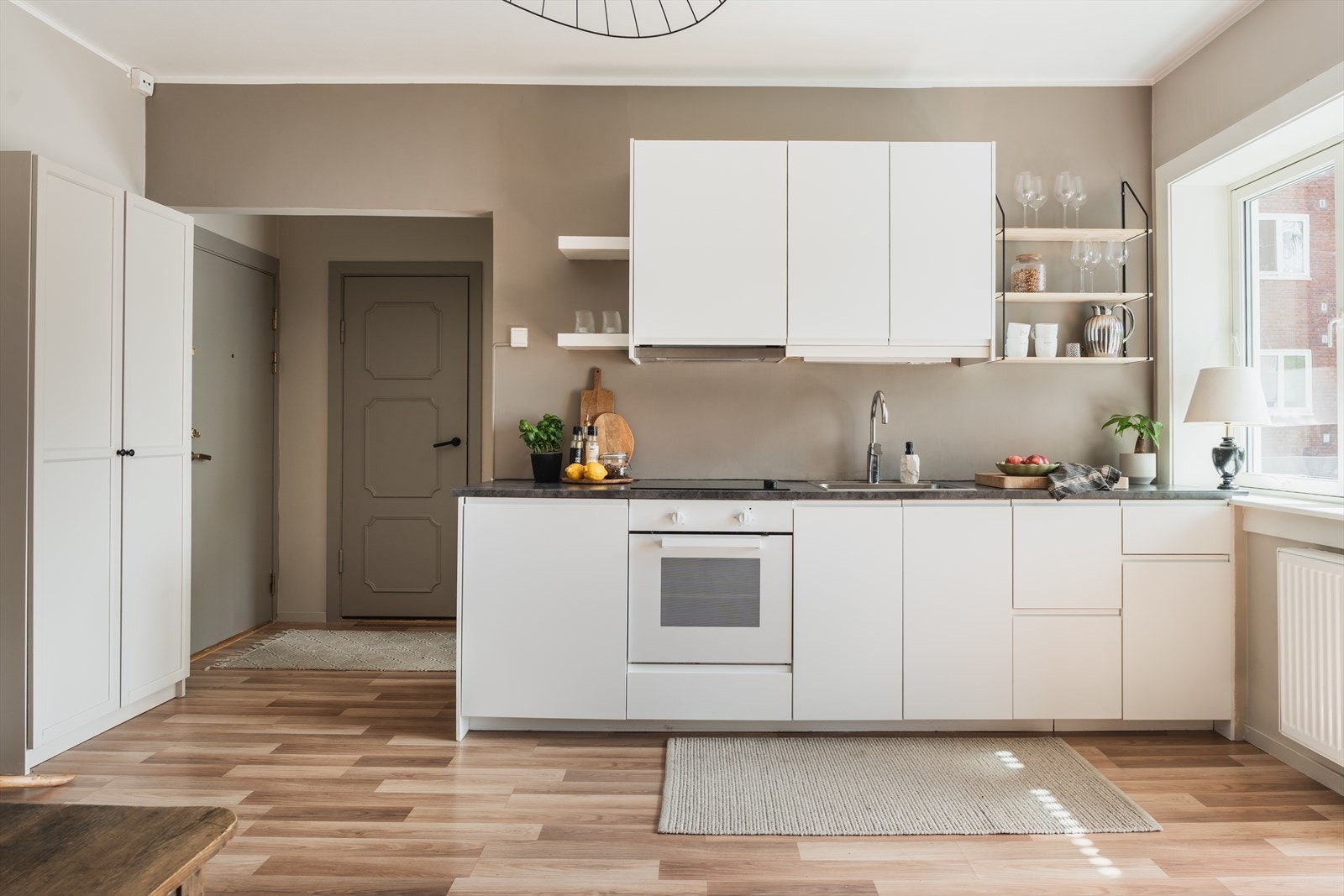 Ikea kjøkkeninnredning fra 2016 med hvite glatte fronter og benkeplate i laminat med nedfelt oppvaskkum og nedfelt keramisk koketopp. Galleribilde