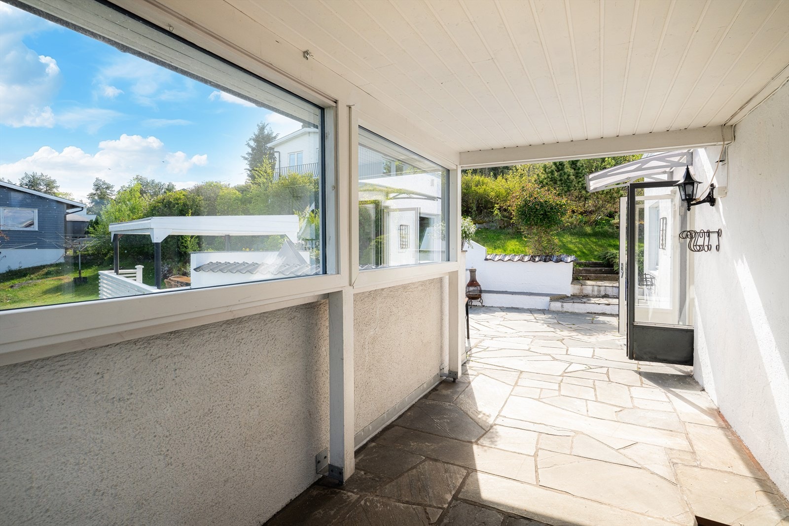 Veranda ut fra stue mot utgangen fra kjøkken og videre ut på uteplassen Galleribilde