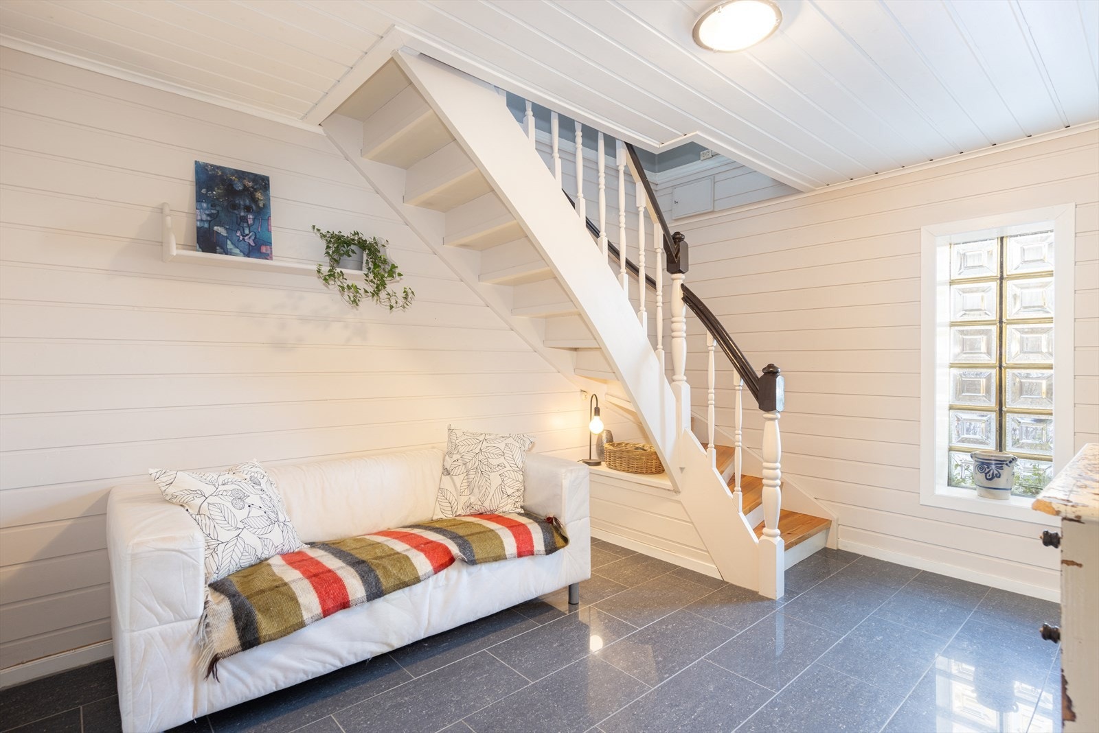 Videre inn ligger hallen som er på 12 m2, med samme, fine overflater, men i tillegg har varmekabler i gulvet. Trapp med lakkerte tette trinn og malte vanger og rekkverk opp til hovedetasjen. Galleribilde