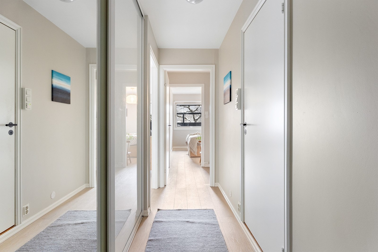 Entréen ønsker deg velkommen med lyse, nymalte flater og enstavs parkett som er gjennomgående i hele leiligheten. Her finner du også skyvedørsgarderobe med speilfronter. Galleribilde