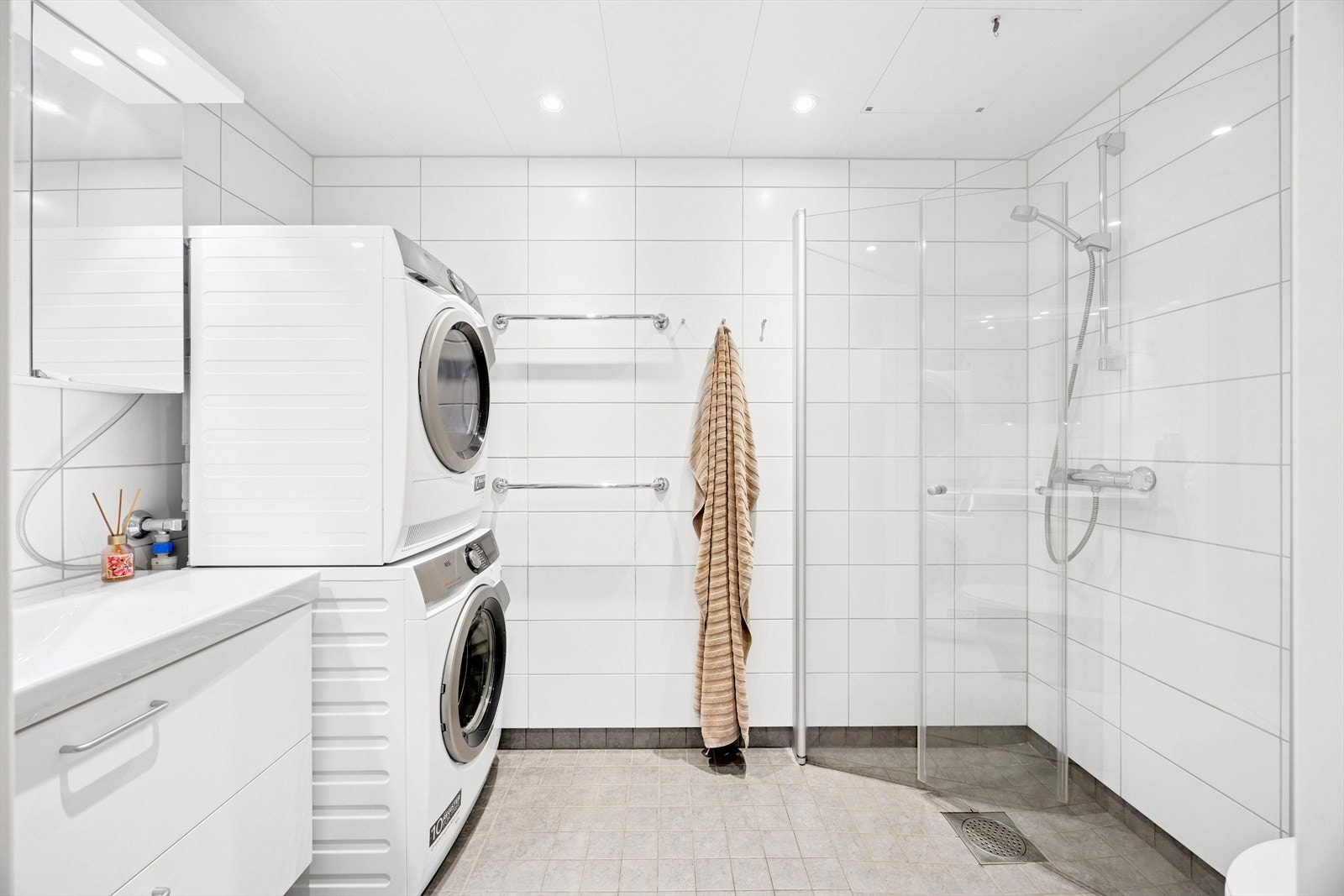 Badet er lyst og romslig med tidløse fliser på vegger og gulv. I taket er det downlights og i gulvet er det varme. Galleribilde