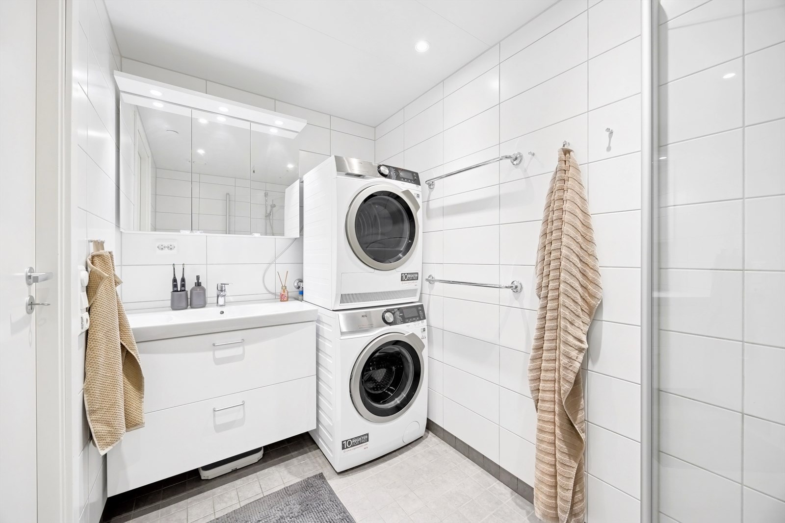 Det er opplegg og god plass for vaskemaskin og tørketrommel. Innredning består av servantskap i hvit glatt utførelse med heldekkende servant og overskap med speildører. Galleribilde