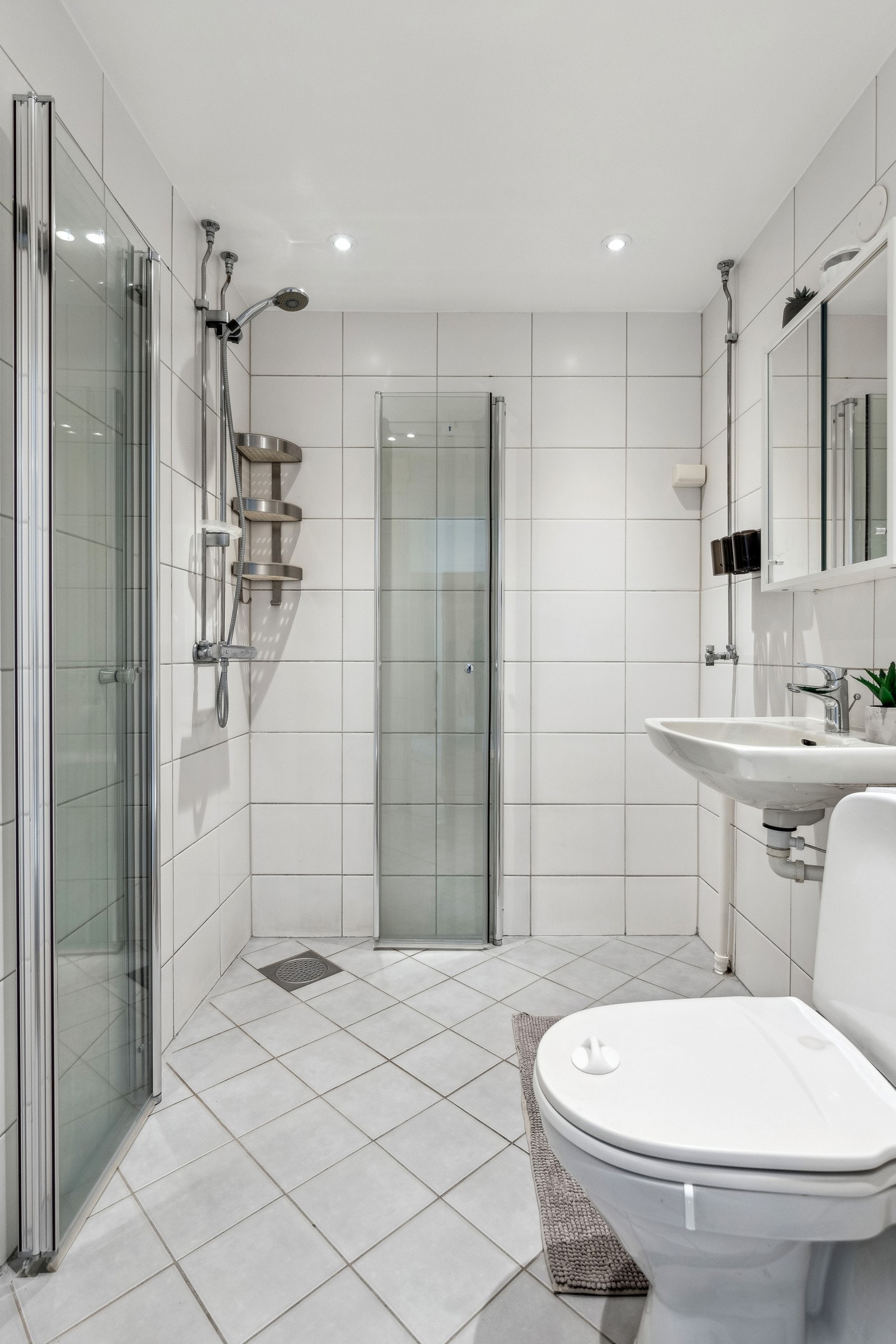 Flislagt baderom modernisert i perioden 2008-2010, med dusjhjørne, vegghengt servant, speilskap og opplegg for vaskemaskin Galleribilde