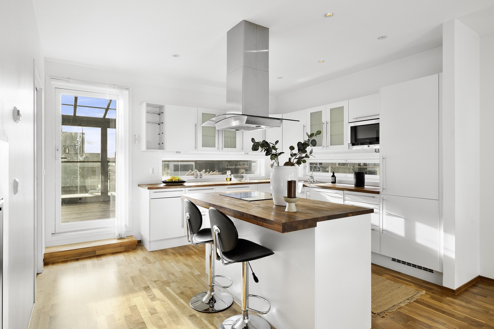 Fra kjøkkenet er det utgang til terrassen som er innglasset. Dette gir et utvidet boarealet som visker ut skillet mellom innendørs- og utendørsområdene. Galleribilde