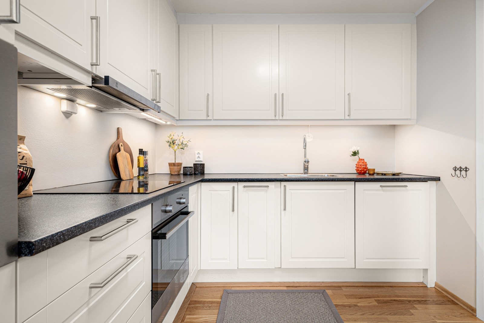 Kjøkkenet er innredet med hvite lakkerte, lett profilerte fronter med laminat benkeplate og rikelig skap- og benkeplass Galleribilde