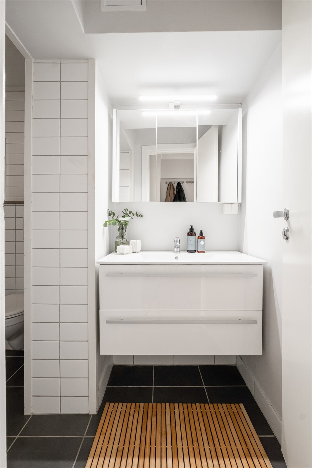 Baderommet er innredet med vegghengt klosett, servant med innredning, speilskap m/lys og dusjhjørne med svingbare glassdører. Galleribilde