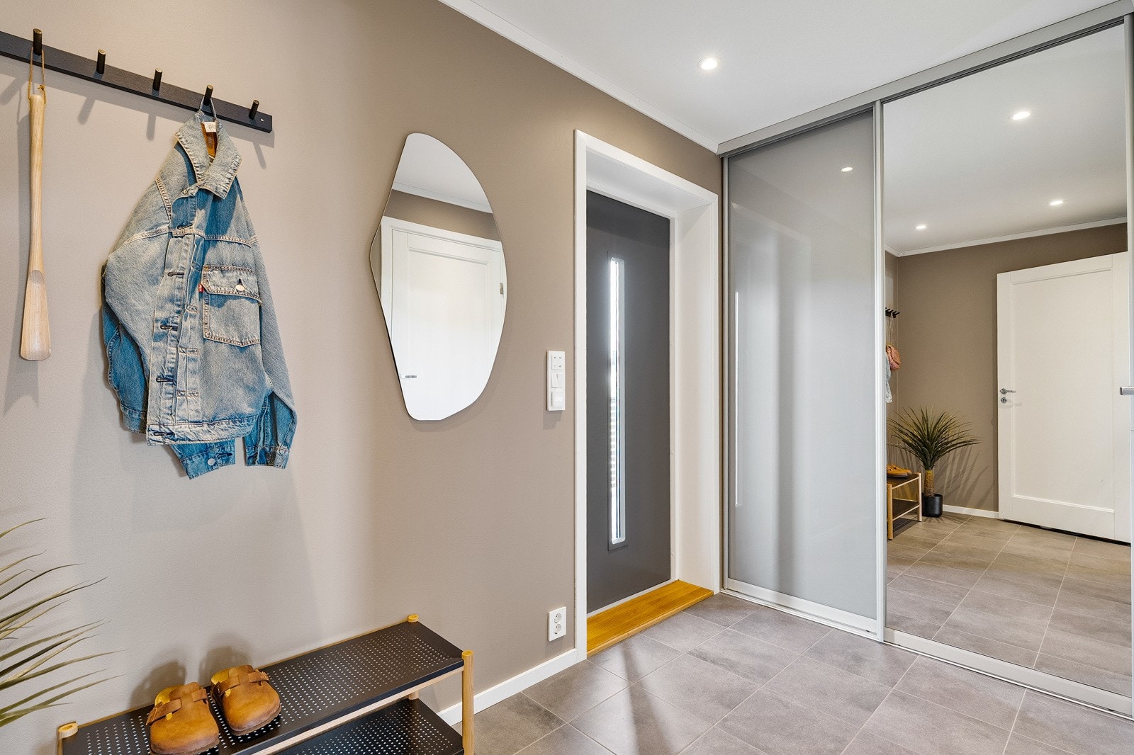 Flislagt entré med skyvedørsgarderobe. Galleribilde