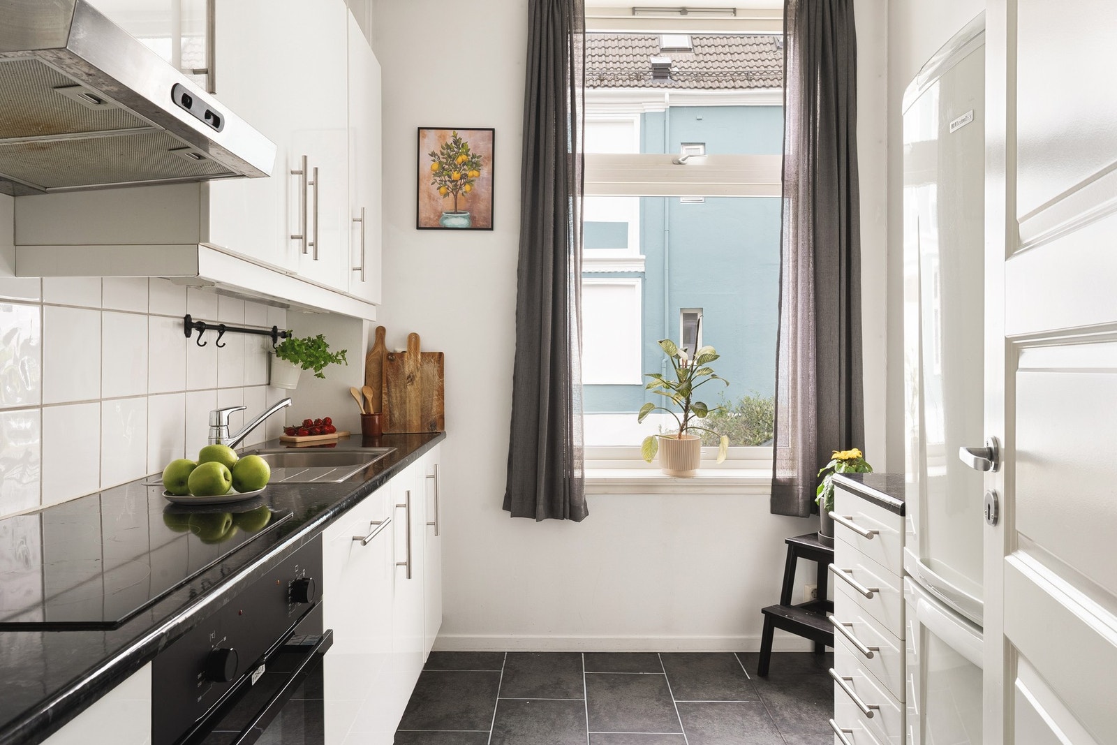 Stilren innredning fra IKEA med slette fronter og laminat benkeplate. Her finnes integrerte hvitevarer som ny stekeovn fra 2024, platetopp, oppvaskmaskin og ventilator. Galleribilde