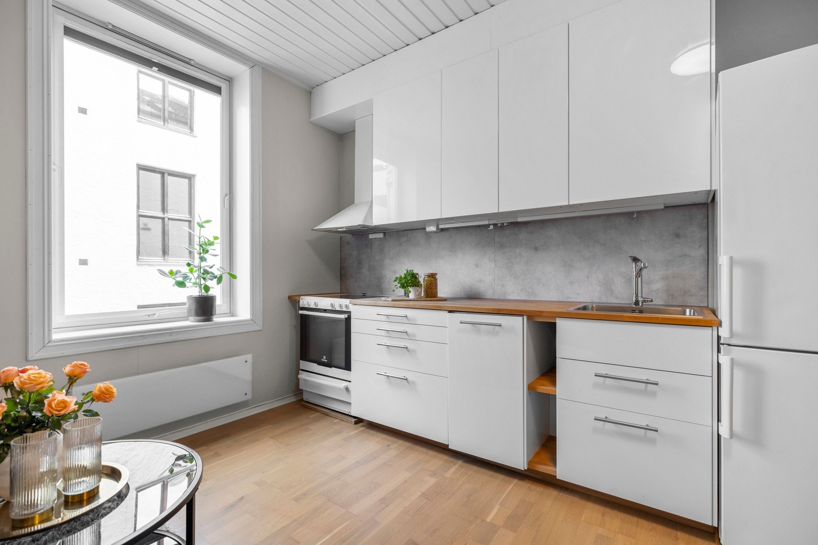 Kjøkkenet byr på glatte, folierte fronter. Heltre benkeplate, opplegg for oppvaskmaskin, komfyr m/topp og frittstående kjøleskap. Galleribilde