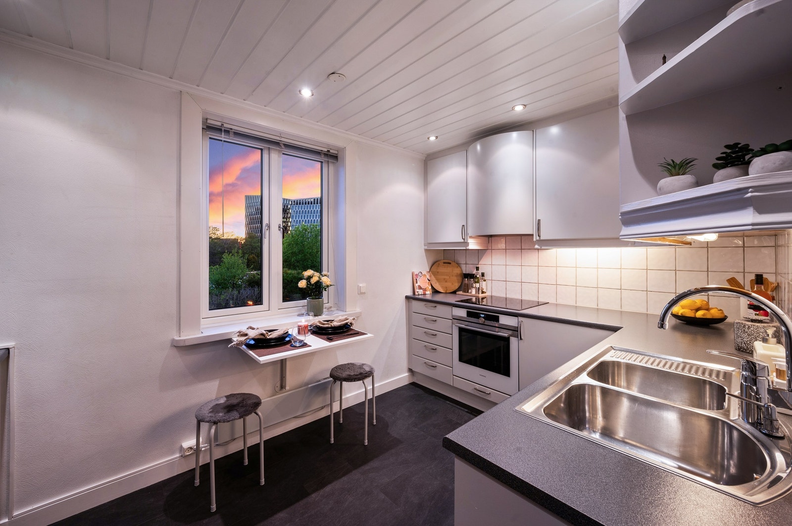 Innredningen består av slette skapfronter og benkeplate av laminat med nedfelt dobbel oppvaskkum i rustfritt stål. Det er flislagt mellom benkeplate og overskap samt belysning under overskap og stikkontakter. Galleribilde