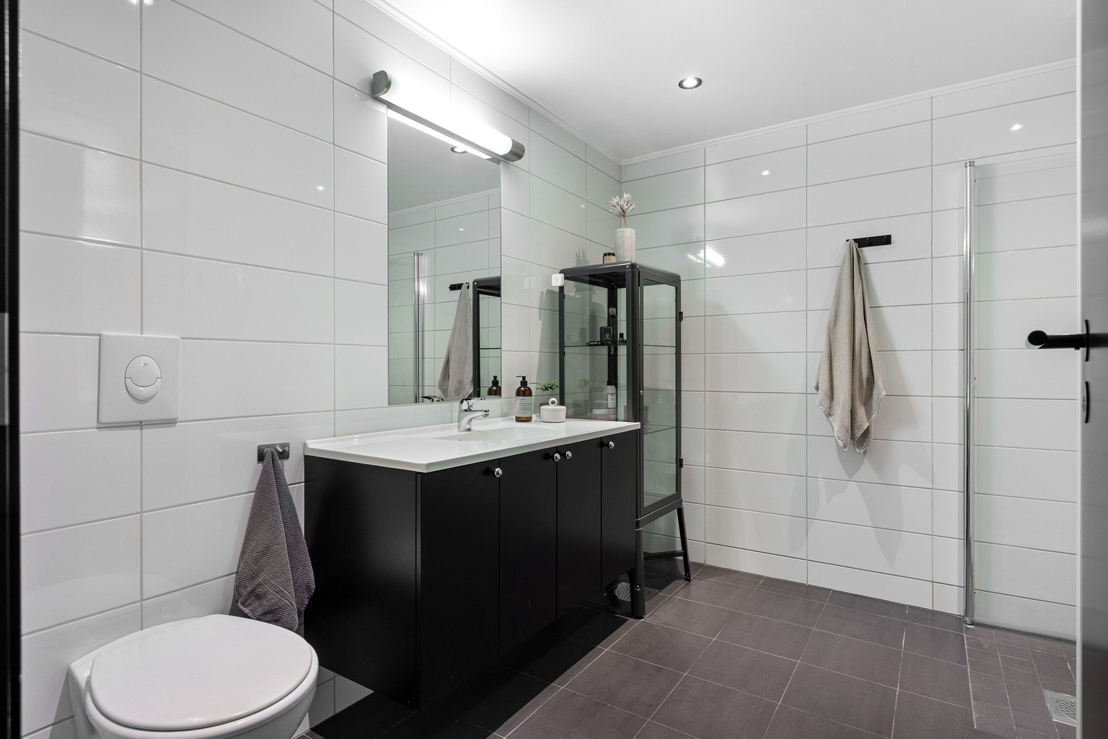 Lyst og pent flislagt baderom med dusj, toalett, vask i innredning. Opplegg for vaskemaskin. Galleribilde