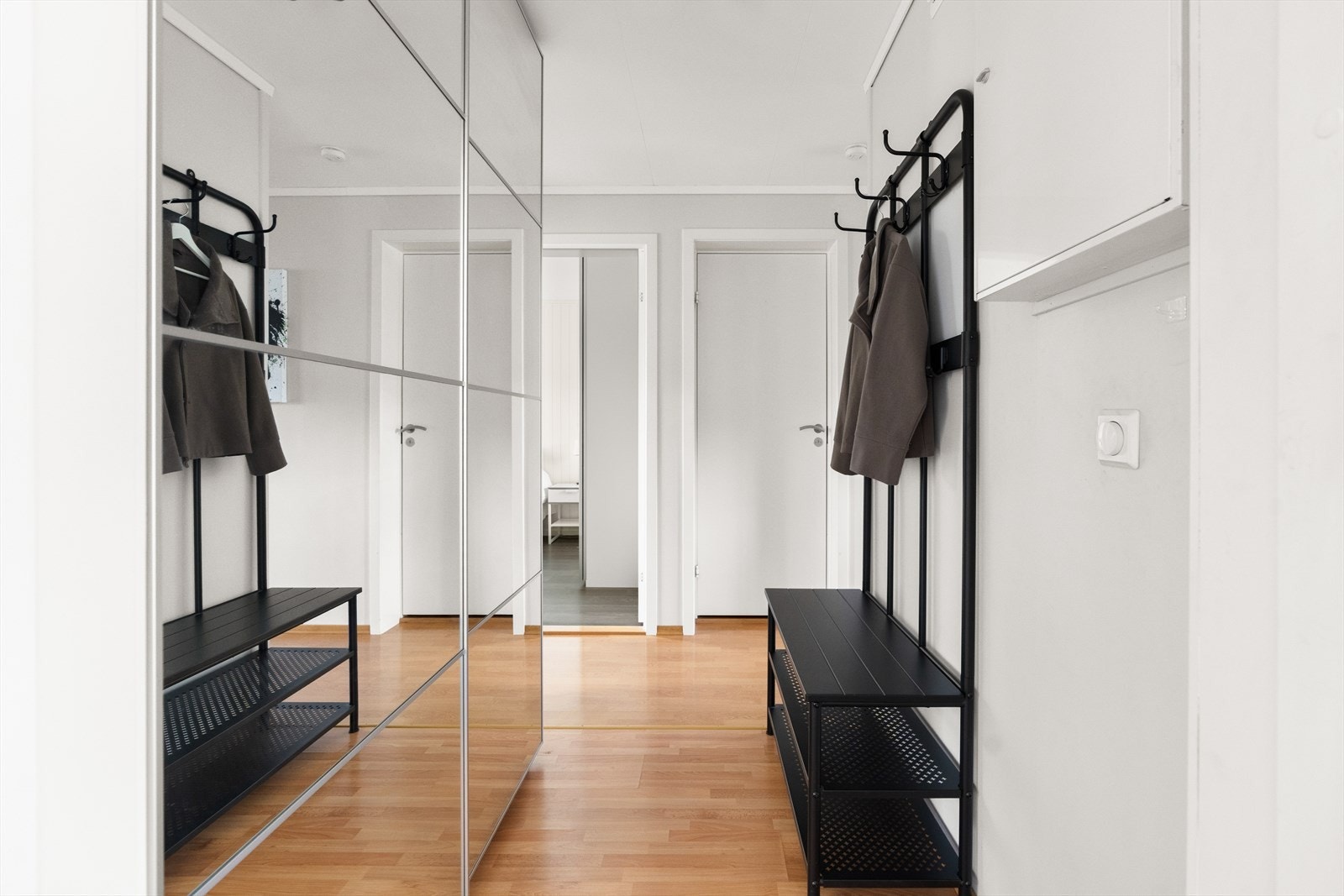 Velkommen inn i en lys og innbydende entré! Her finner du en praktisk skyvedørsgarderobe med speildører som både gir romfølelse og sørger for smart oppbevaring. Galleribilde
