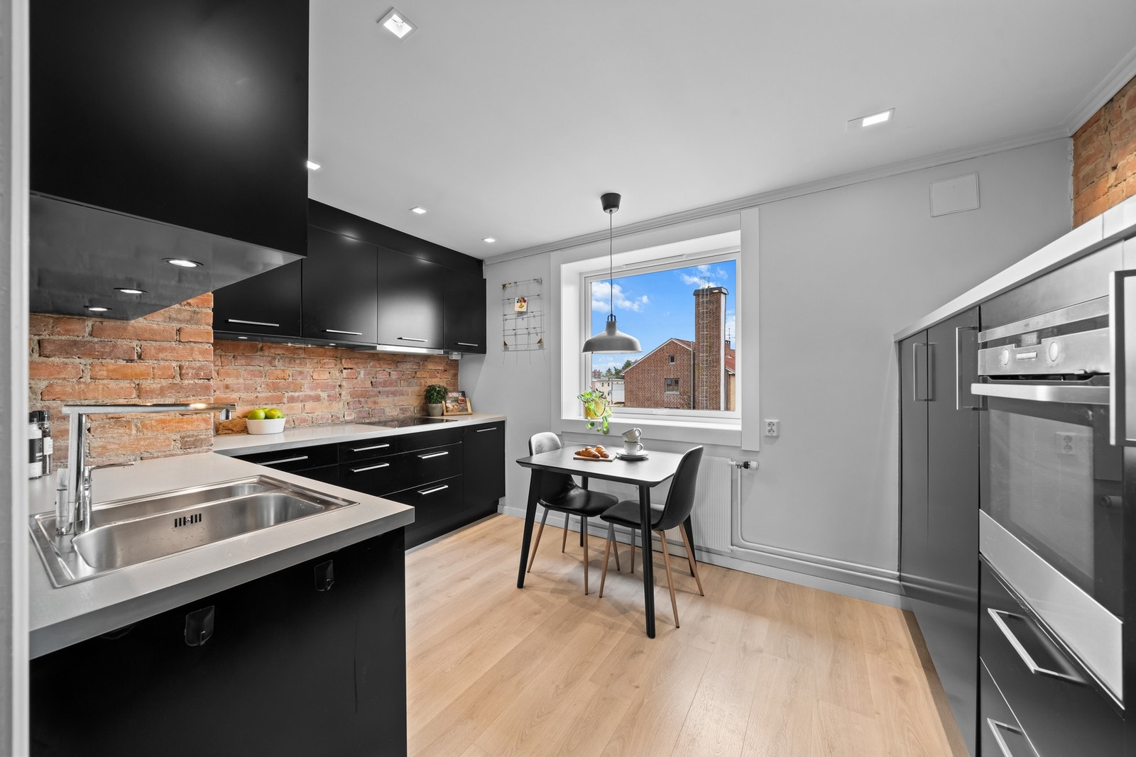 Innredningen fra Ikea har sorte, glatte fronter, takoppforede skap og lys laminatbenkeplate med nedfelt kum i stål Galleribilde