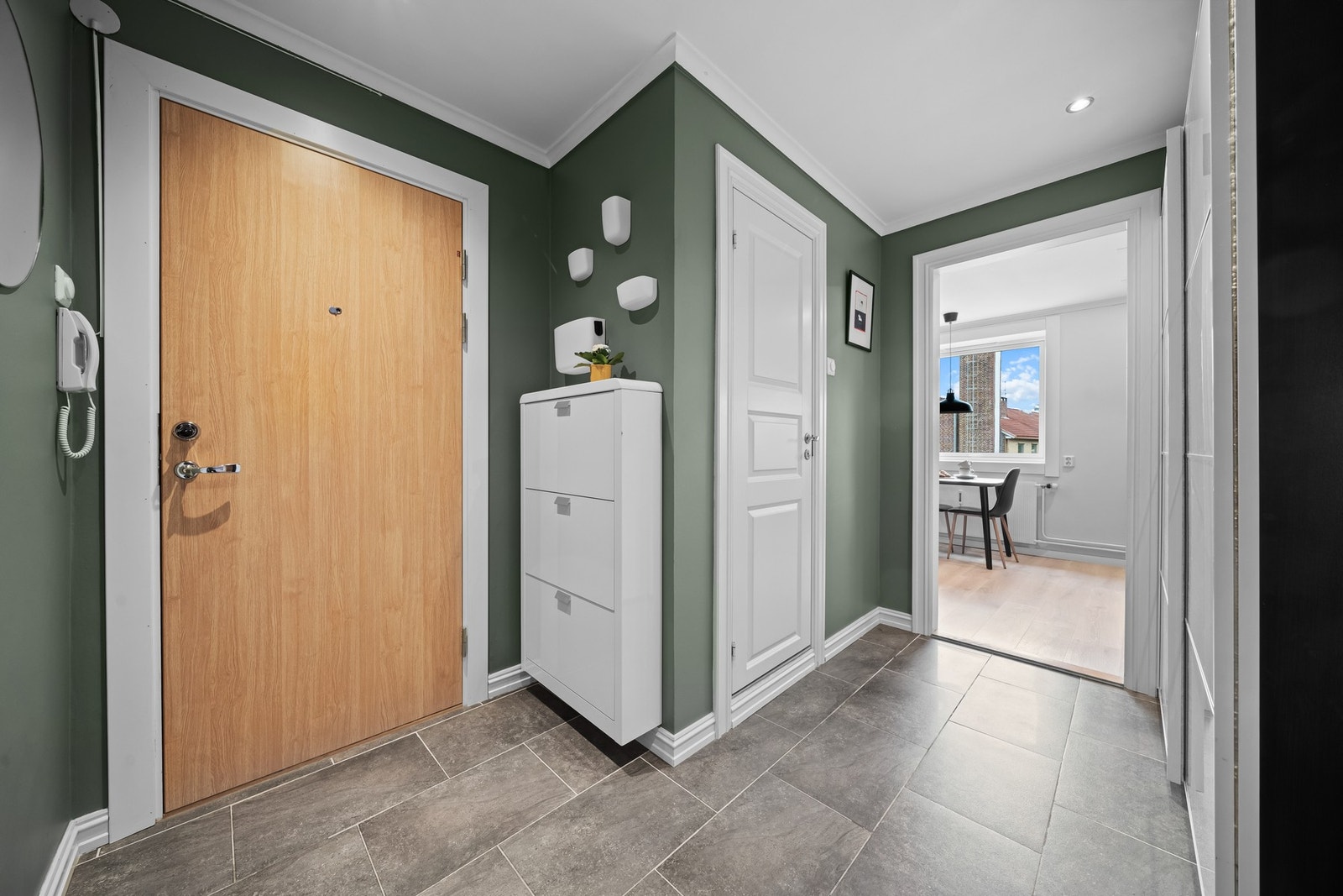 Vel inne blir vi ønsket velkommen i en pen entré med grønnmalte vegger og grå fliser på gulvet - en stilren kombinasjon som kan passe de aller fleste Galleribilde