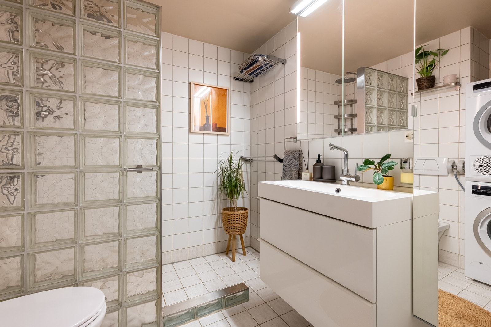 Badet er utstyrt med vegghengt servantinnredning, servant, vegghengt speilskap med integrert lys og dusjhjørne med vegg av glassbyggerstein og dusjarmatur tilkoblet hånddusj og regndusj. Galleribilde