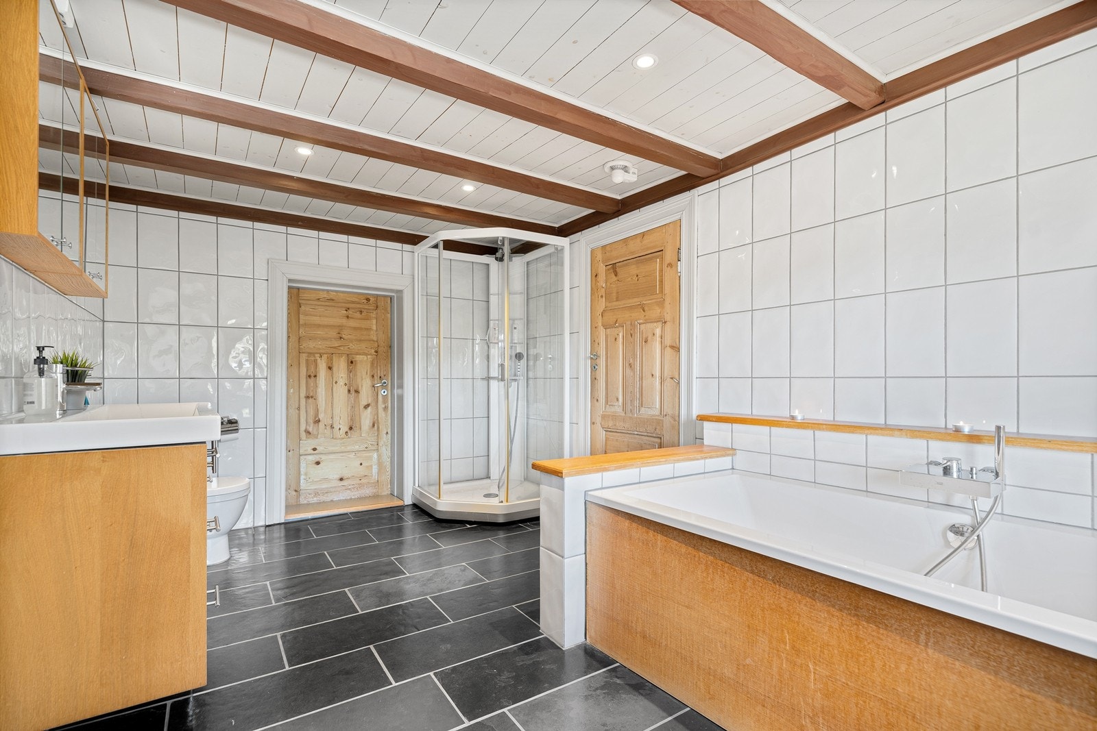 Badet i 2 etg. med varmekabler, badekar, dusjkabinett, wc, servant med skuffer og skap under og overskap. Inngang garderobe. Galleribilde