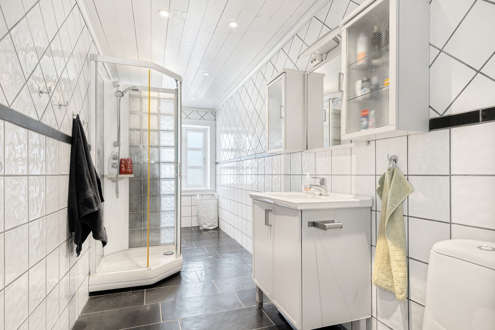 Badet i 1. etg. med dusjkabinett, servant med skap under og overskap, wc. Galleribilde