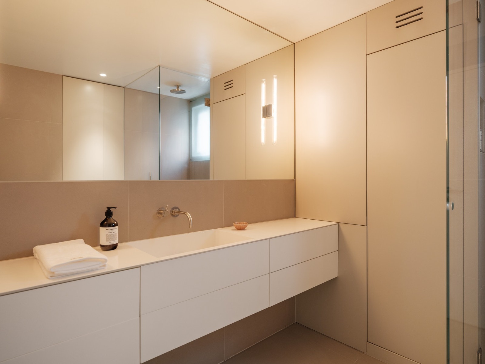 Baderomsinnredning i corian, bestående av benkeskap og integrerte veggskap med glatte fronter. Galleribilde