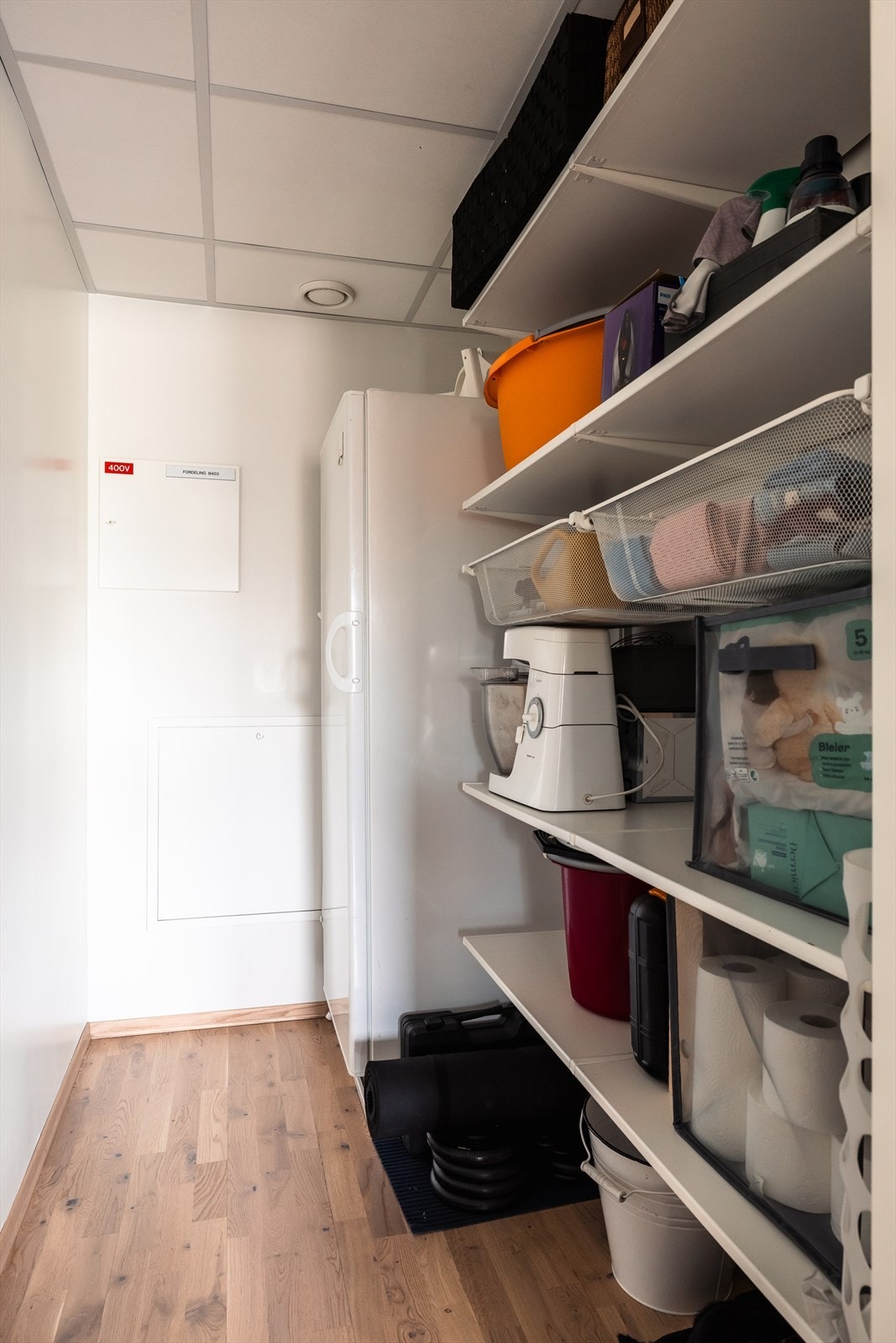 Fra stuen er det tilgang til boligens innvendige bod. Her er det hyller for oppbevaring og system. Selger har valgt å ha et stort og fullverdig kjøleskap på kjøkkenet og det er god plass til fryser innerst i boden som vist her. Galleribilde