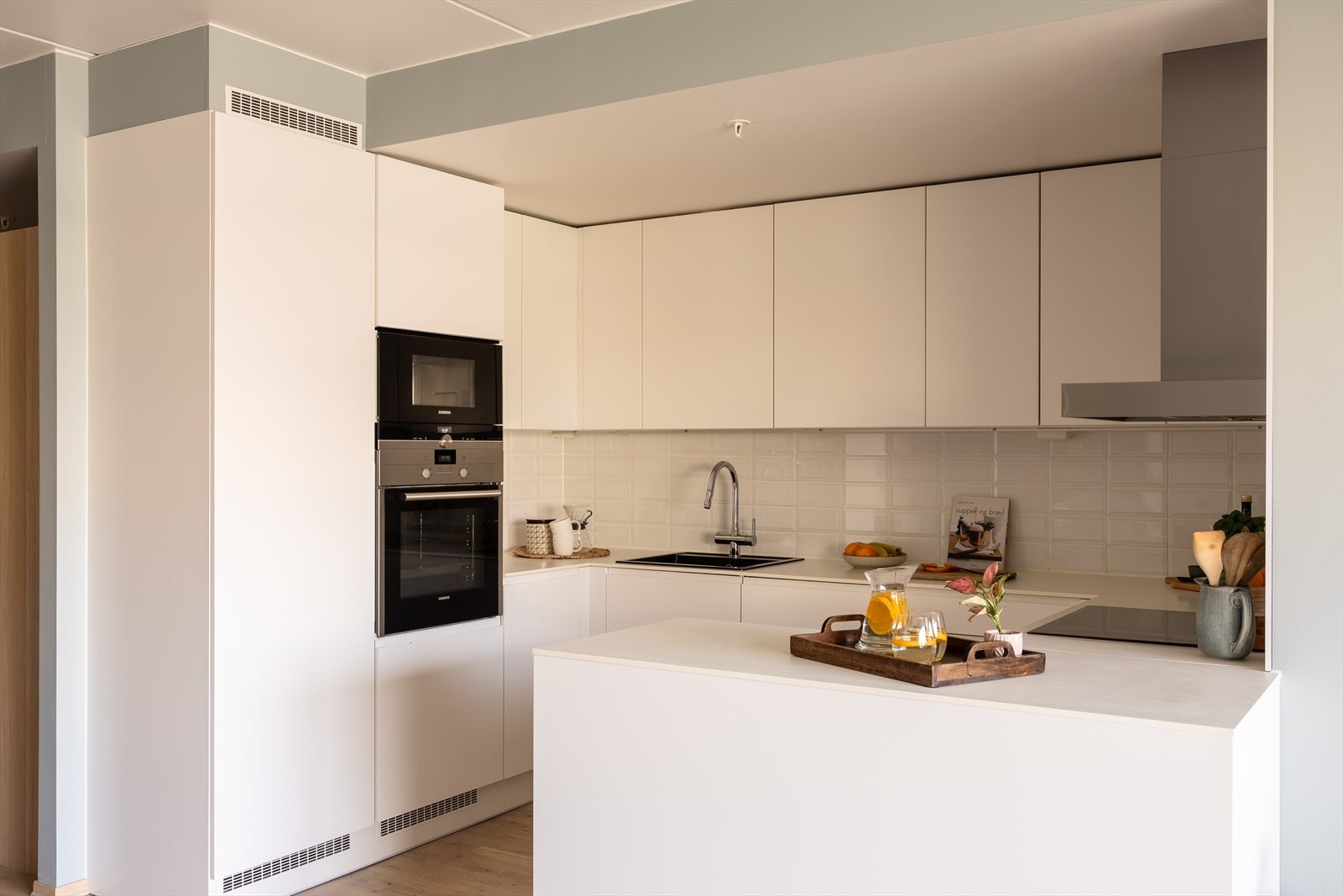 Et lyst og lekkert kjøkken med integrerte hvitevarer og mye både skap- og benkeplass. Galleribilde