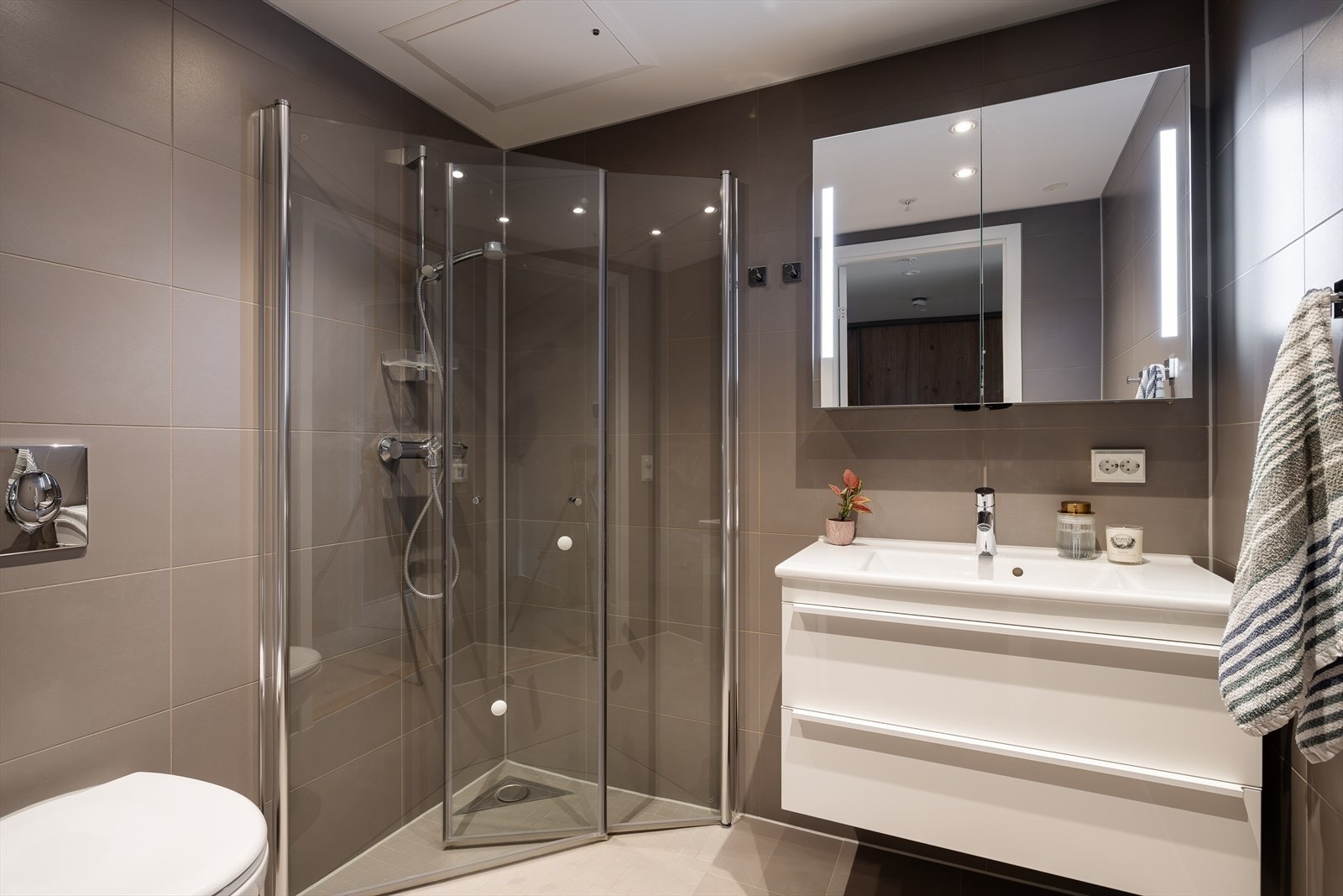 Det andre badet er også romslig med både dusj, toalett, og vask med skapinnredning. Også her er det downlights i taket og gulvvarme. Dette badet er perfekt som privat bad og ligger i soveromsdelen. Galleribilde