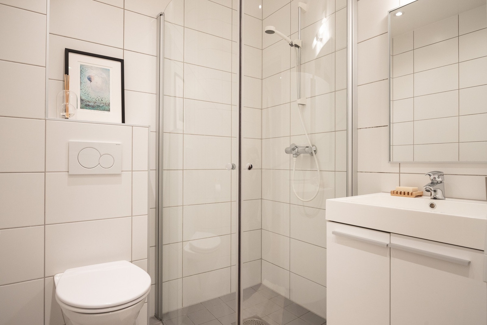 Badet består av servantskap med nedfelt servant, vegghengt toalett og dusjhjørne med innfellbare dusjdører. Galleribilde