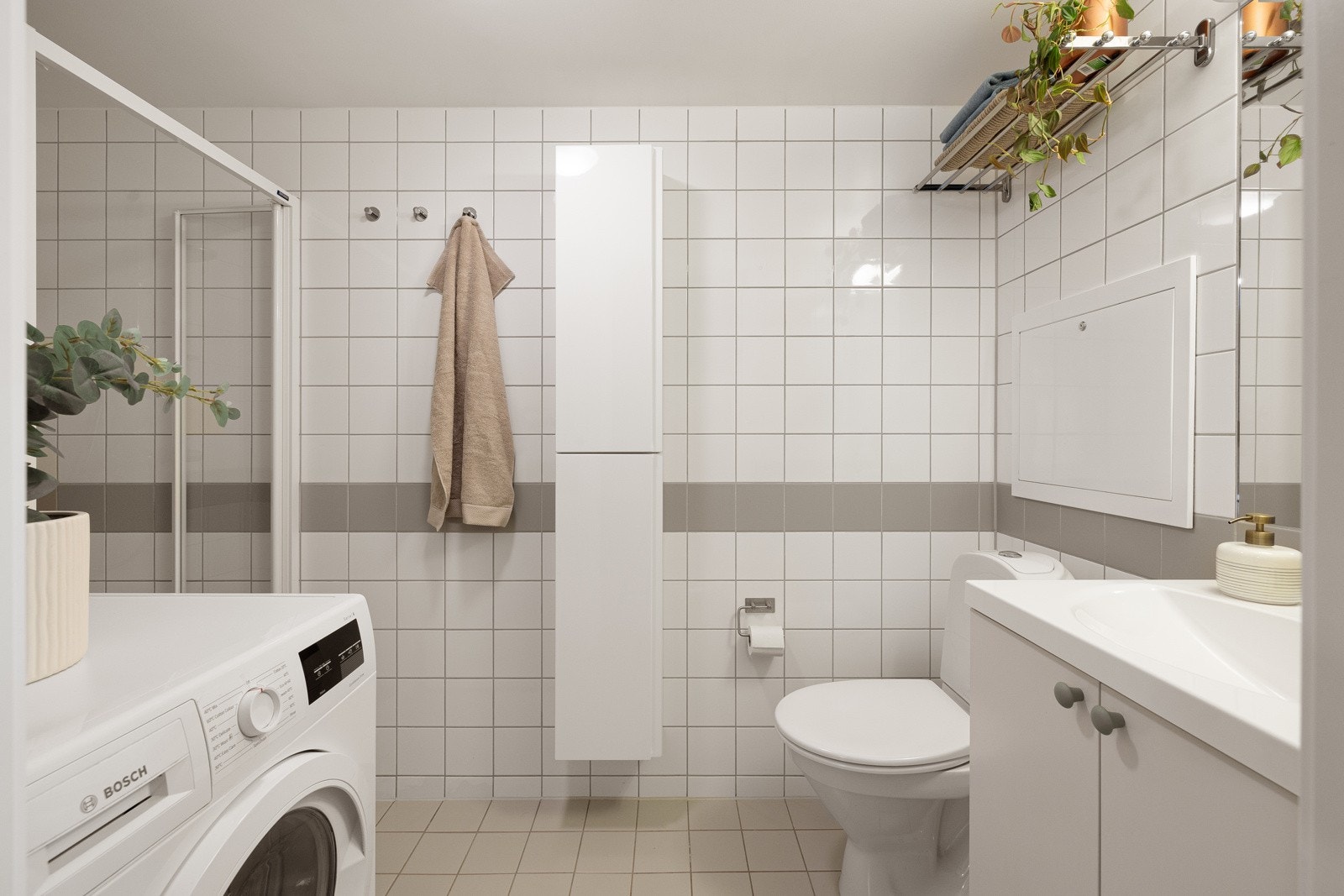 Romslig, flislagt baderom fra byggeår med dusjssone med innfellbare dusjdører. Galleribilde