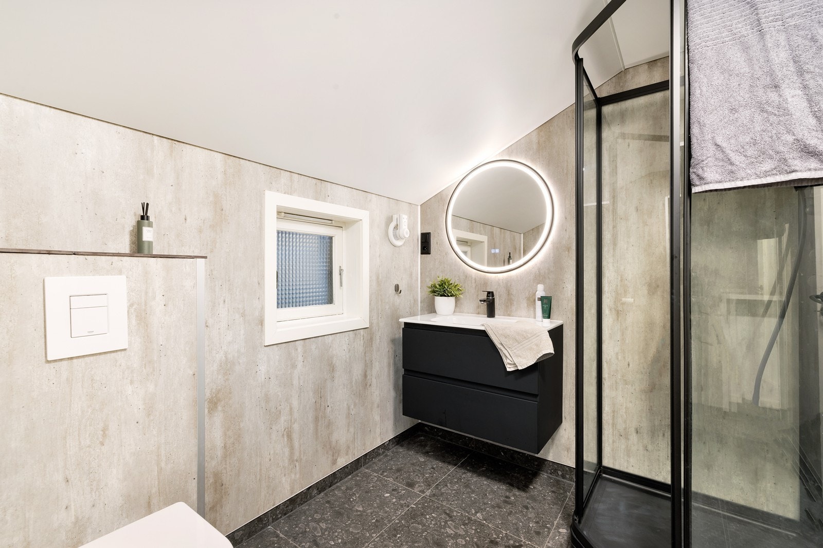 Flott bad med fliser og varmekabler i gulv. Våtromsplater på vegger. Badet har dusjkabinett, servant med underskuffer og vegg hengt toalett. Galleribilde