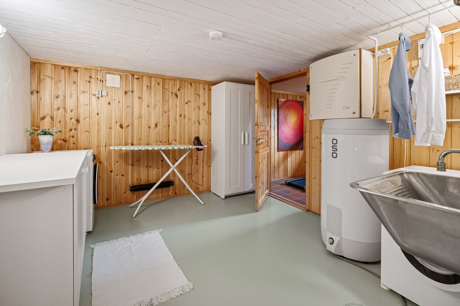 Boligens vaskerom er innredet med utslagsvask og benk med skapinnredning. Opplegg for vaskemaskin og plass til tørketrommel. Galleribilde