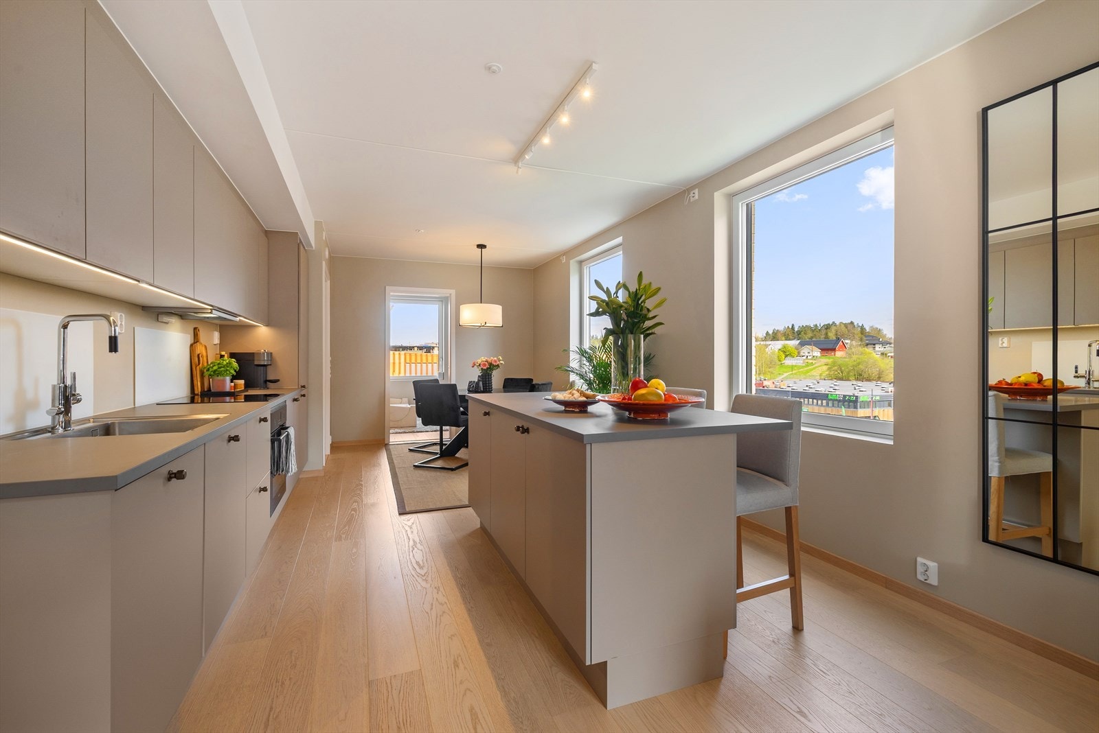 Kjøkkenet fra HTH er påkostet med tilvalg og har en moderne innredning i en tidløs gråbeige utførelse med håndtak og en mørk grå benkeplate. Galleribilde