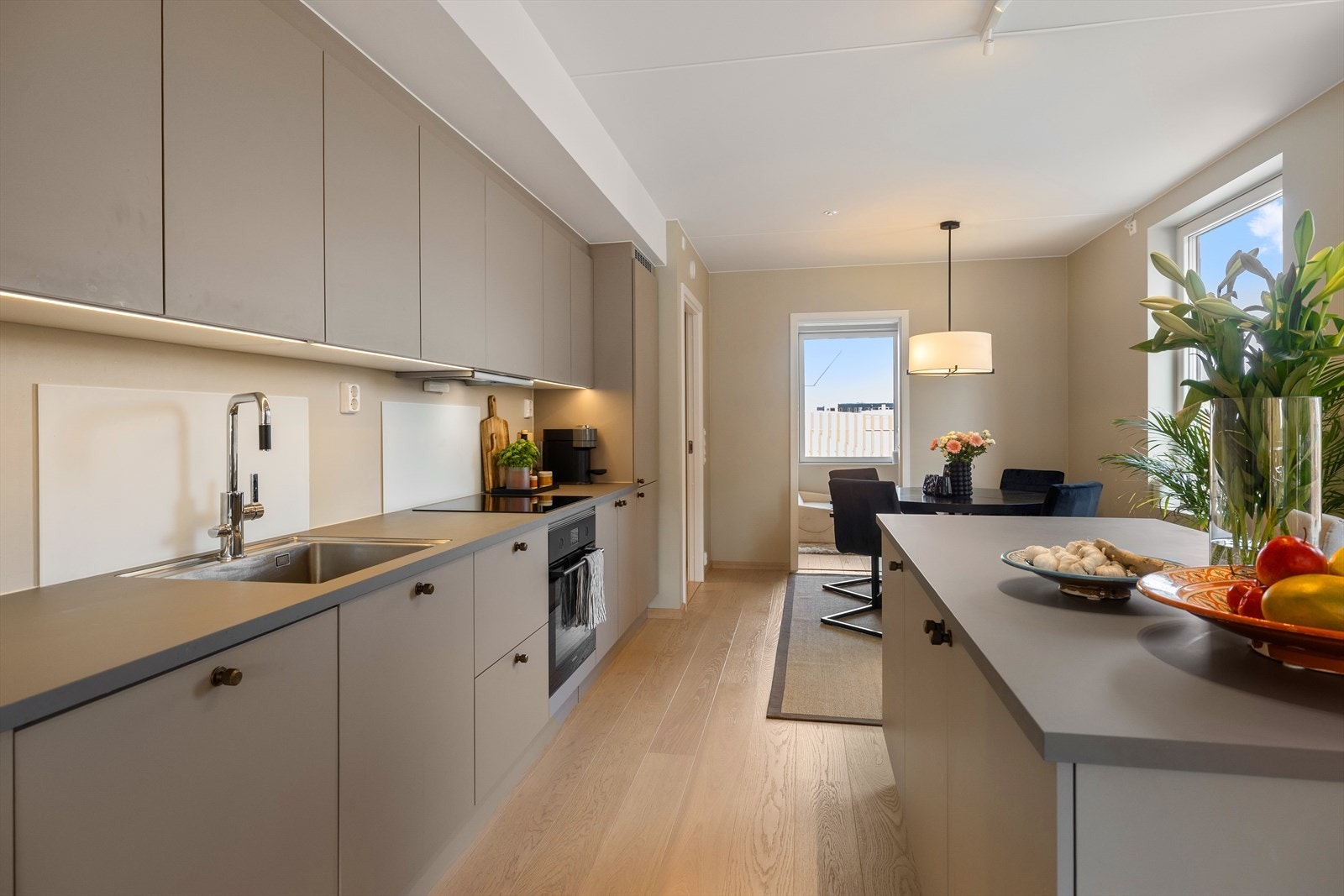 Det er et pent parkettgulv mot en lys beigetone på vegg. Sammen gir dette et delikat og moderne uttrykk på kjøkkenet. Galleribilde