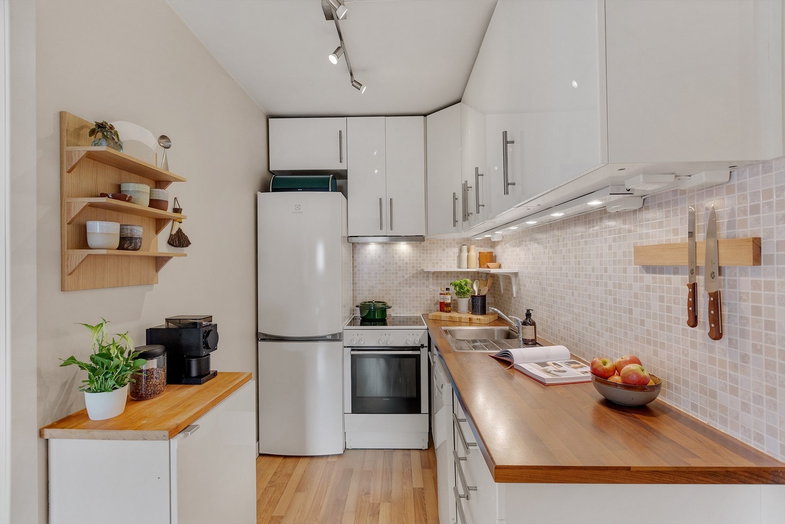 Kjøkkeninnredning fra Ikea fremstår med glatte fronter. Laminert benkeplate med oppvaskkum og 1-greps blandebatteri. Lys under overskap, ventilator med kullfilter. Integrerte hvitevarer med: oppvaskmaskin av smal type. Galleribilde