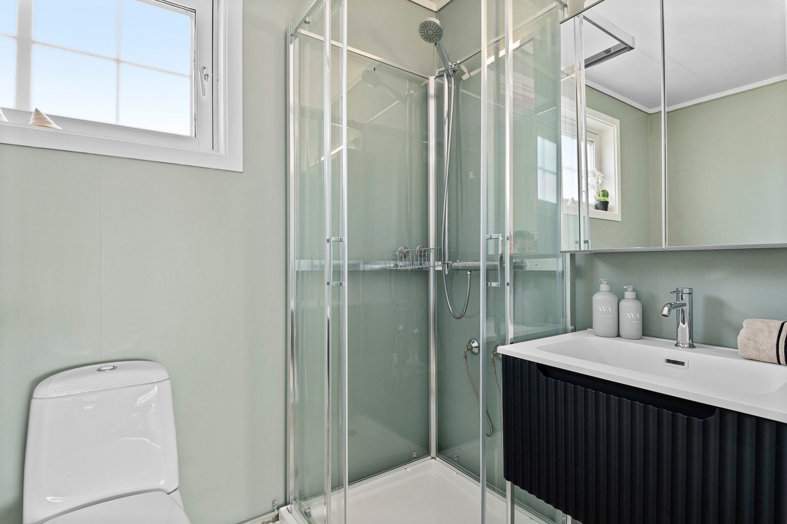 Badet i hovedboligen er innredet med dusjkabinett, servant, overskap, wc og opplegg for vaskemaskin. Galleribilde